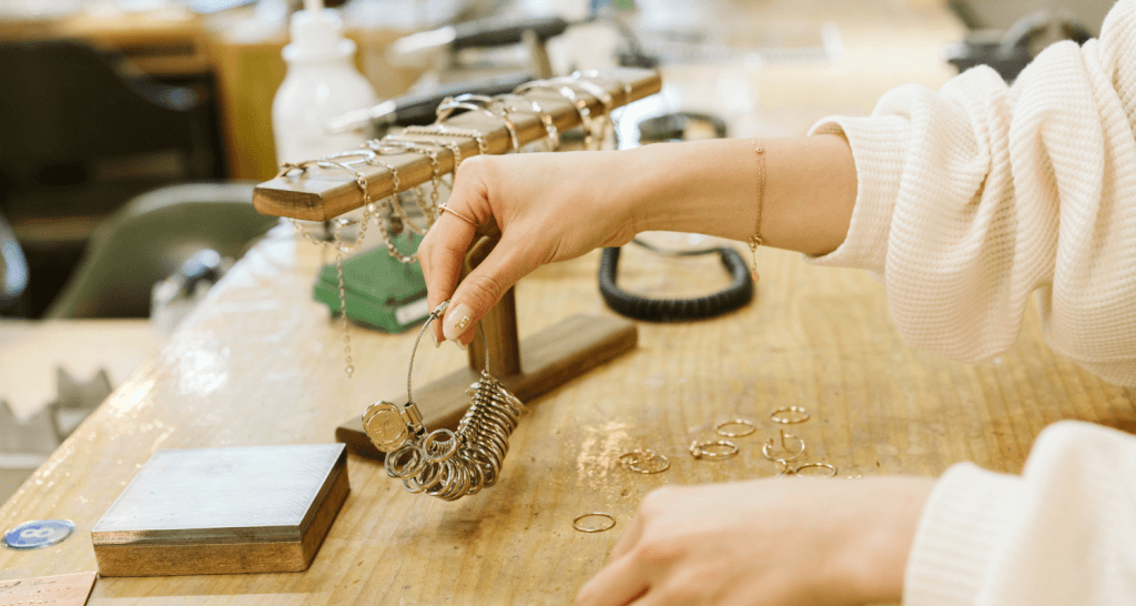 Zoom sur une main de femme tenant un échantillon de bague pour connaitre la taille des clients