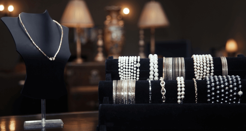 Vitrine avec plusieurs présentoirs mettant en avant un collier et des bracelets argentés et de perles